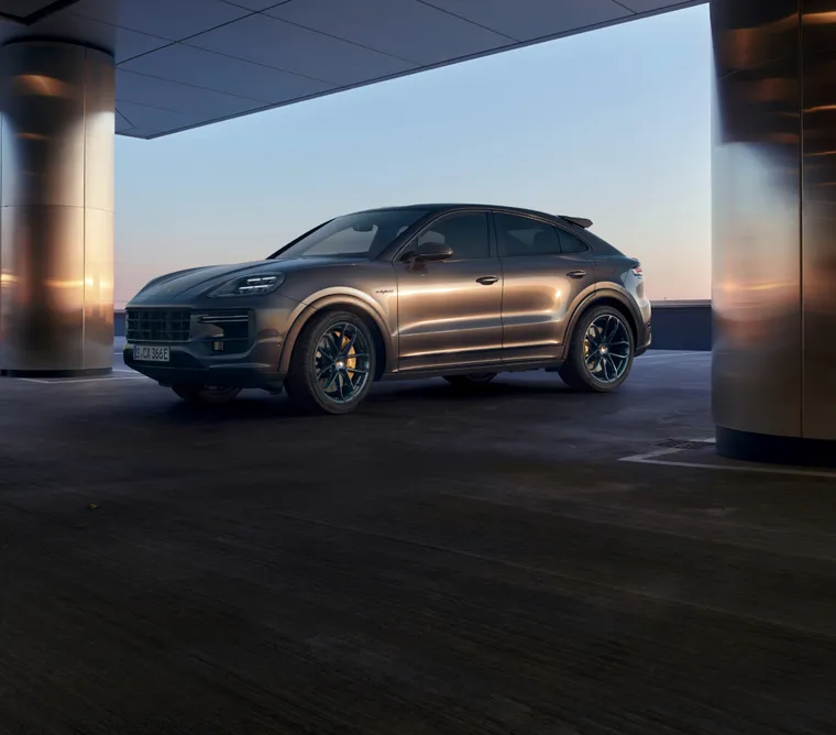 Porsche Cayenne Turbo E-Hybrid Coupé com Pacote GT em Cinzento Quartzite Metalizado parado num ambiente urbano. Vista lateral.