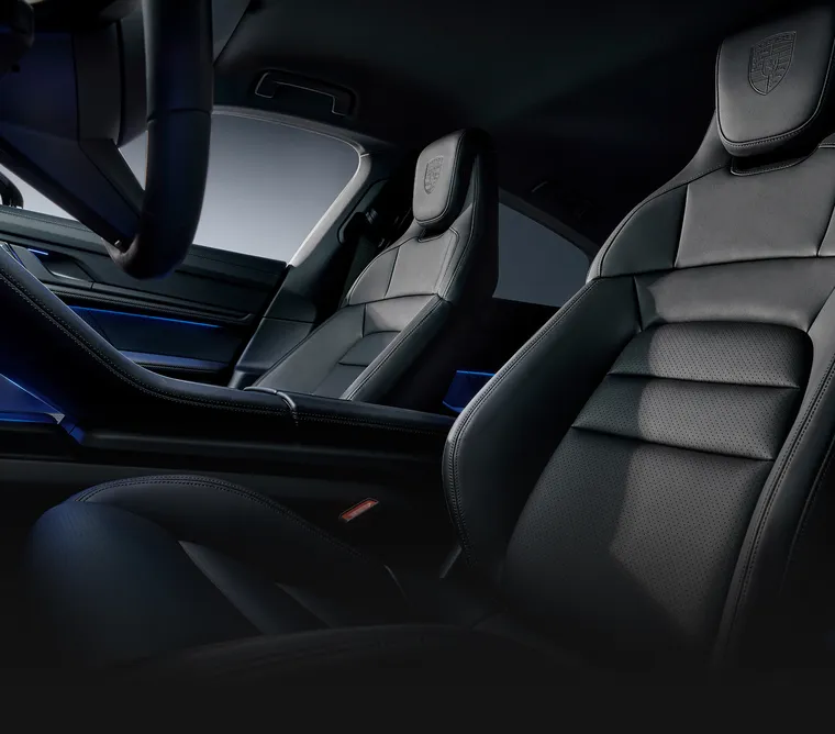 Blick in den Innenraum des Porsche Taycan 4S Black Edition mit Fokus auf die Komfortsitze mit geprägtem Porsche Wappen auf den Kopfstützen.