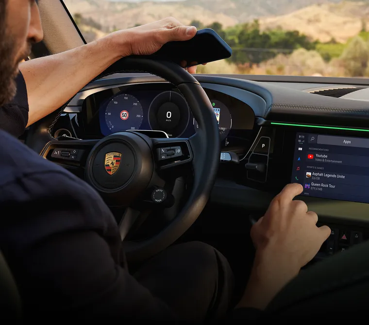Porsche Macan 4S interior. View into the cockpit. Man using smartphone.