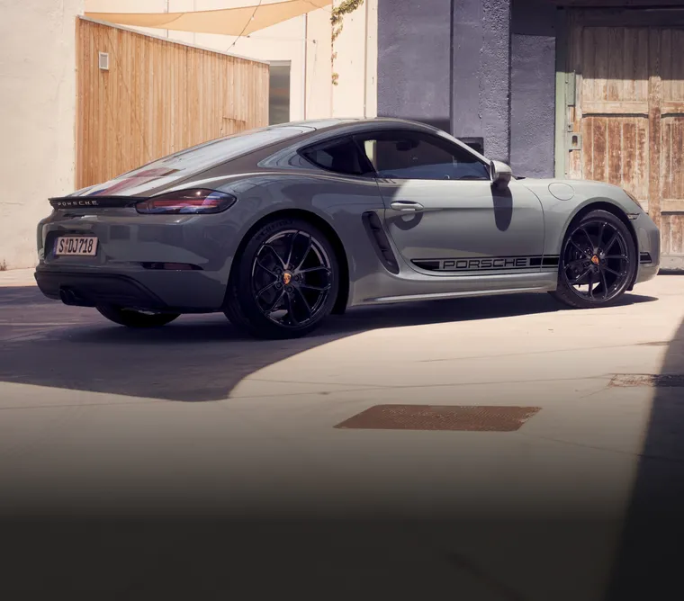 附黑色對比色套件的冰極灰色保時捷 718 Cayman Style Edition 停在一片居民區。車尾和車側圖