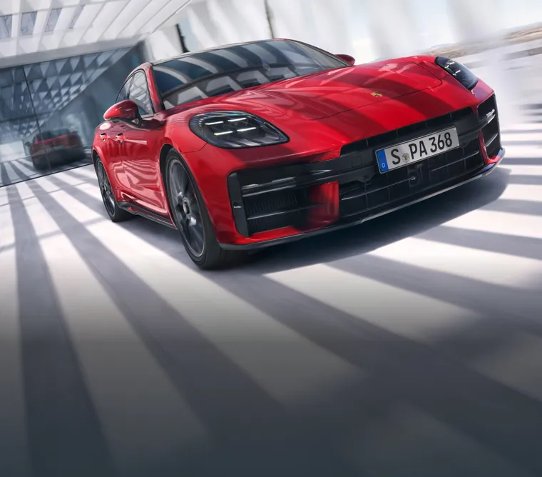 Un Porsche Panamera GTS en color Rojo Carmín recorre la ciudad. Vista desde delante de la parte delantera.