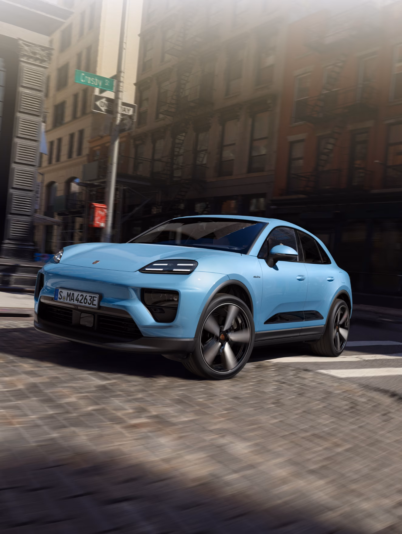 Porsche Macan in Frozen Blue Metallic driving through the city. Front and side visible.