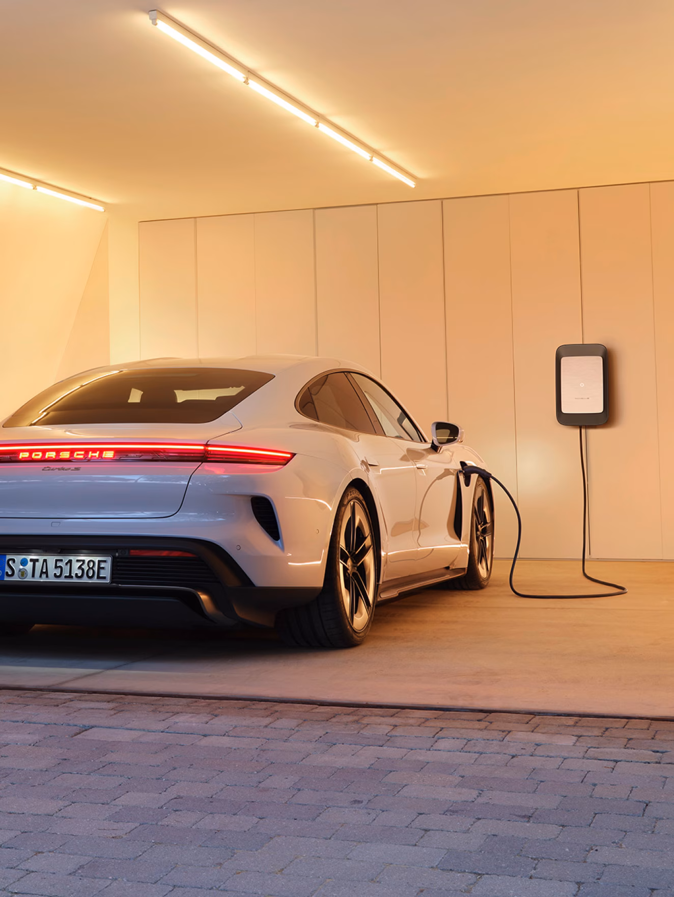 Porsche Taycan Turbo S in Ice Grey Metallic charging. View of rear end.