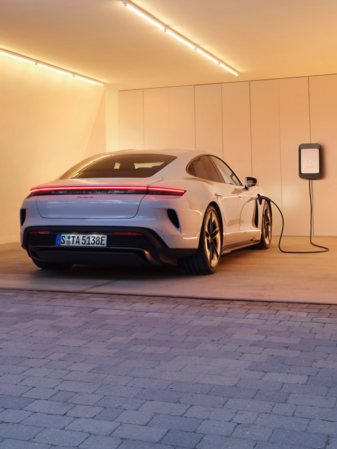 A Taycan Turbo S Sport being charged using a wall charger at home.