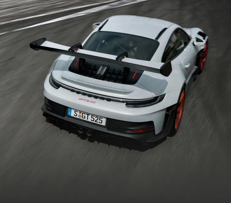 The Porsche 911 GT3 RS in Ice Grey Metallic driving on a rack track. Top rear view of the rear end.
