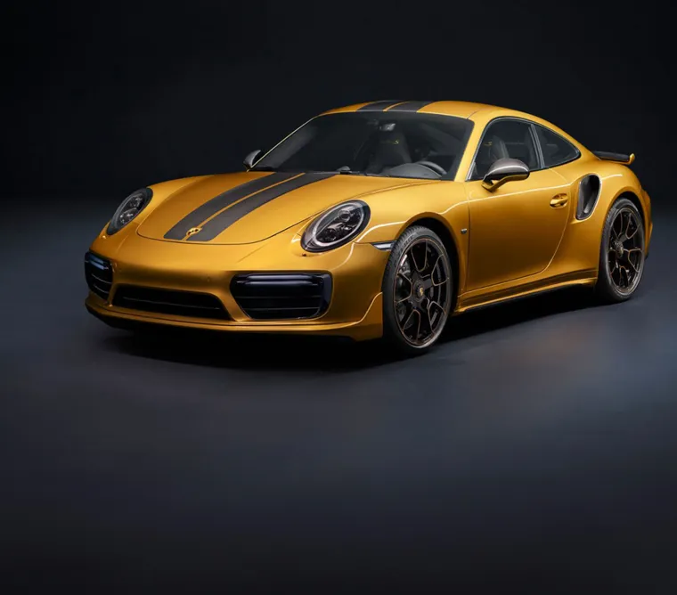 View of the front and side of a Porsche 911 Turbo S in Golden Yellow Metallic. 