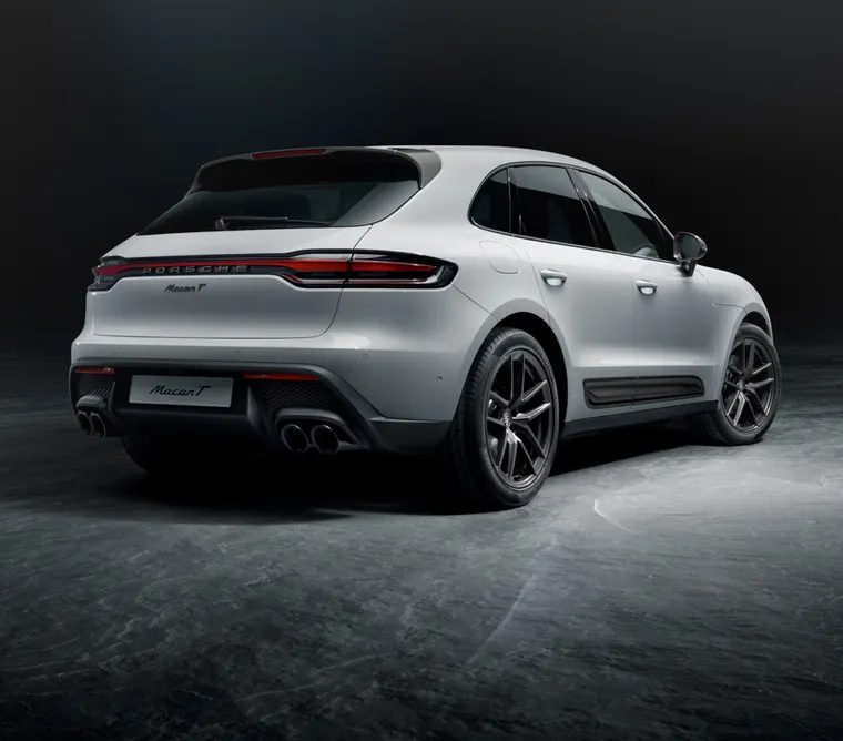Porsche Macan T in White in front of a dark background. View of rear end.