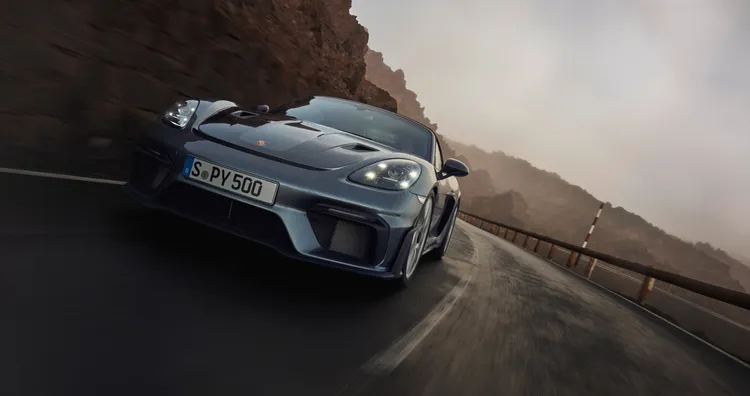 コーナーを走るバナジウムグレー メタリックのポルシェ 718 スパイダー RS フロントビューとサイドビュー