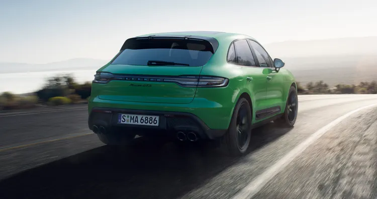 田舎道を走るパイソングリーンのMacan GTS。リアビューとサイドビュー
