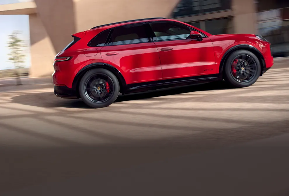 Vue latérale d’un Porsche Cayenne GTS en Rouge Carmin en mouvement.
