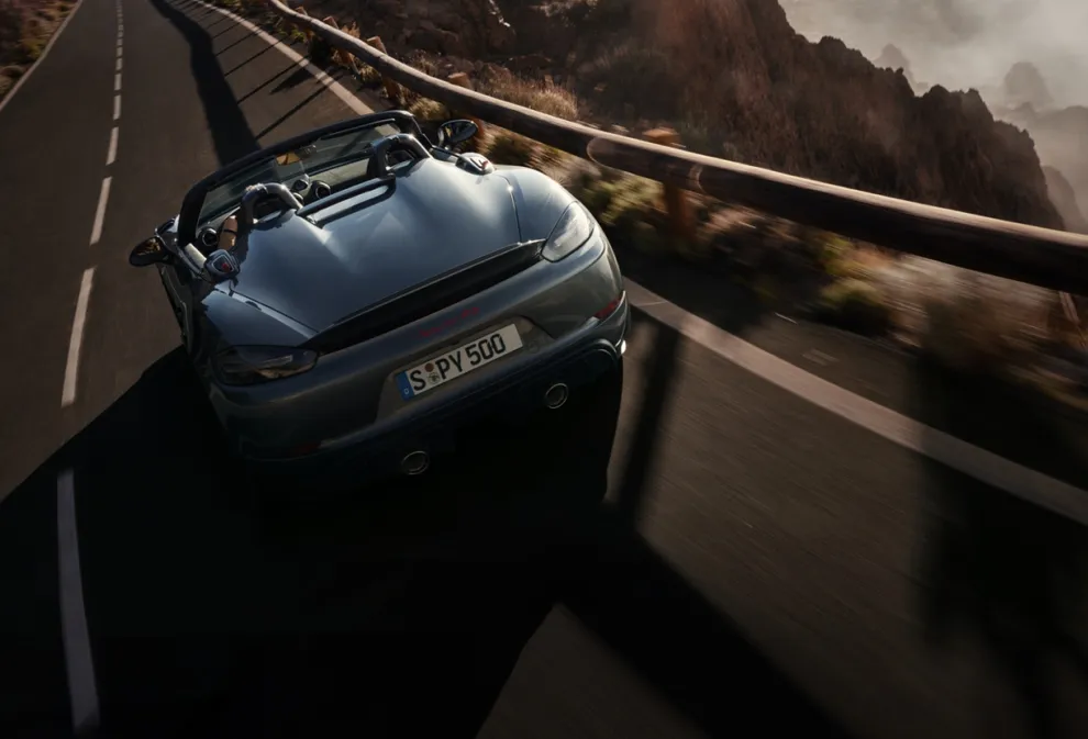 Porsche 718 Spyder RS na cor Cinzento Vanádio Metalizado a deslocar-se na estrada. Vista de baixo da traseira e da lateral.