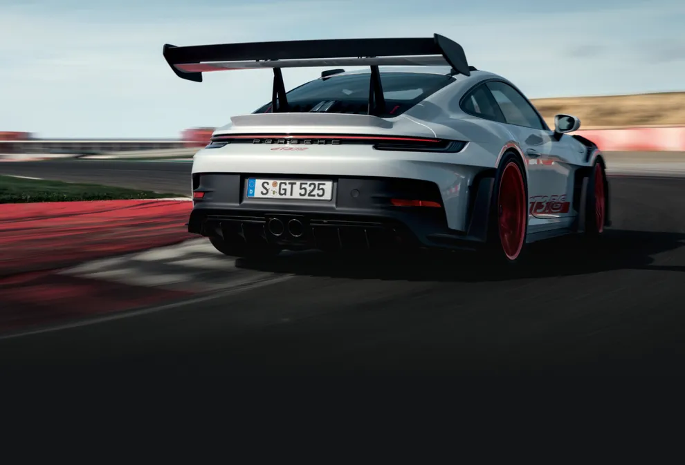 The Porsche 911 GT3 RS in Ice Grey Metallic driving on a rack track. View of the rear end.