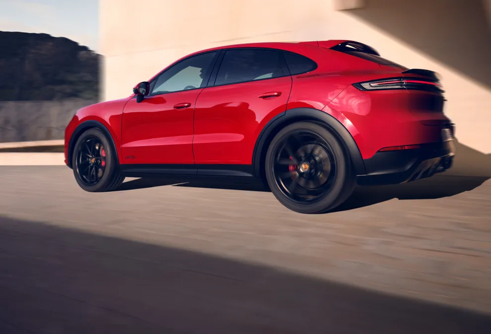 <p>Vista da lateral e traseira de um Porsche Cayenne GTS em movimento na cor vermelho carmim.</p>