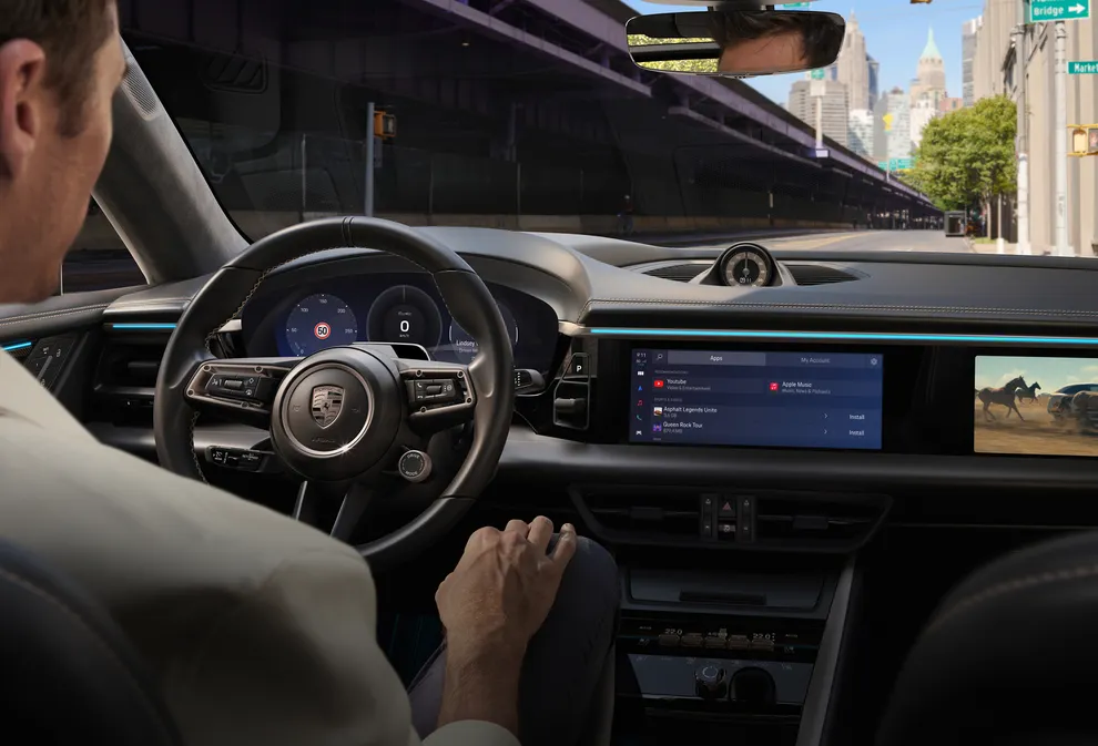 Intérieur du Porsche Macan Turbo. Vue du cockpit. Un homme utilise son smartphone.