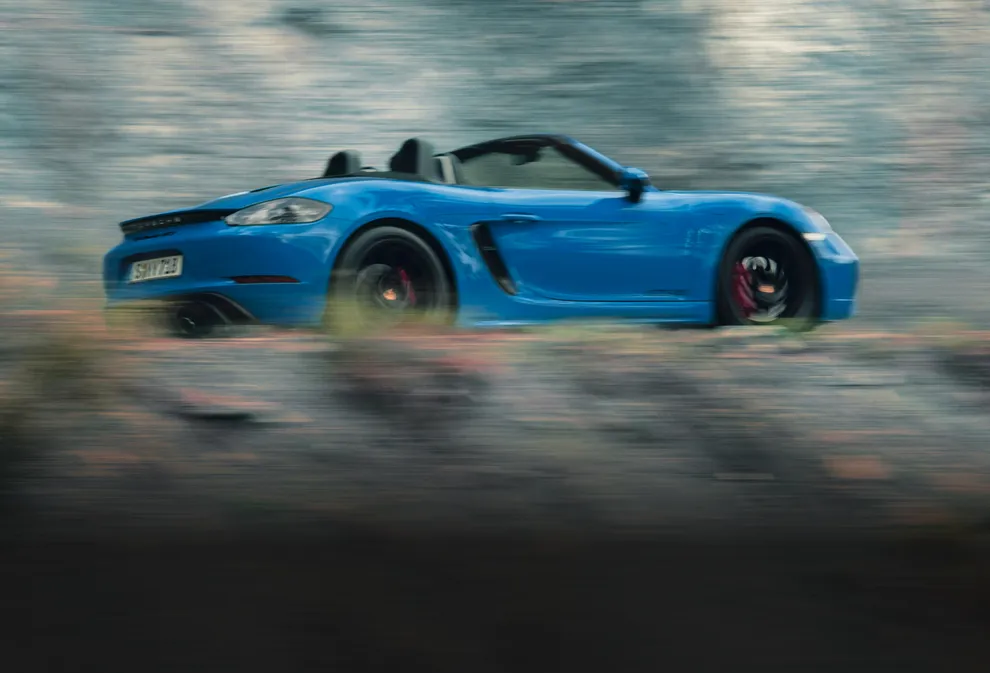鯊魚藍保時捷 718 Boxster GTS 4.0 行駛在山麓的山路上。車側圖