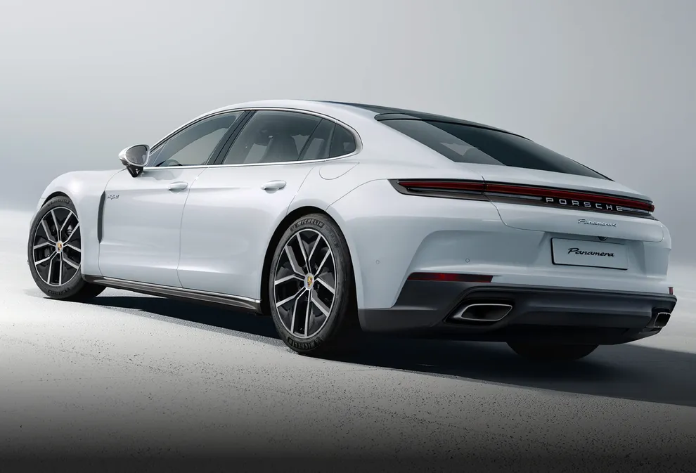 La Porsche Panamera 4 E-Hybrid Executive in Bianco Carrara metallizzato su sfondo grigio chiaro. Vista da dietro su posteriore e laterale.