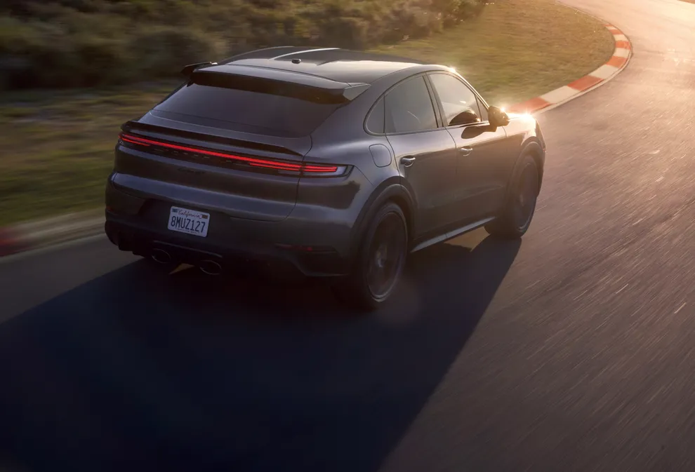 Porsche Cayenne Turbo GT цвета серый металлик (Quarzite Grey Metallic) движется по круговой трассе. Вид сзади и сбоку.