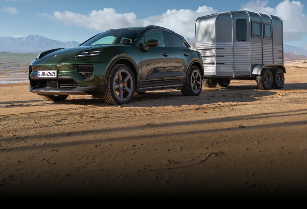 Porsche Macan 4S in Oakgrünmetallic fährt Steigung hinauf. Heck und Seite sichtbar.