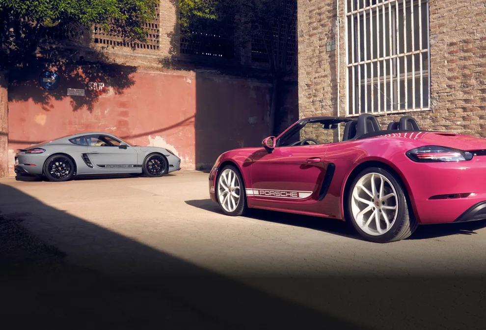 Porsche 718 Boxster Style Edition in Ruby Star Neo with White Contrast Package parked in front of 718 Cayman Style Edition in Arctic Grey with Black Contrast Package.