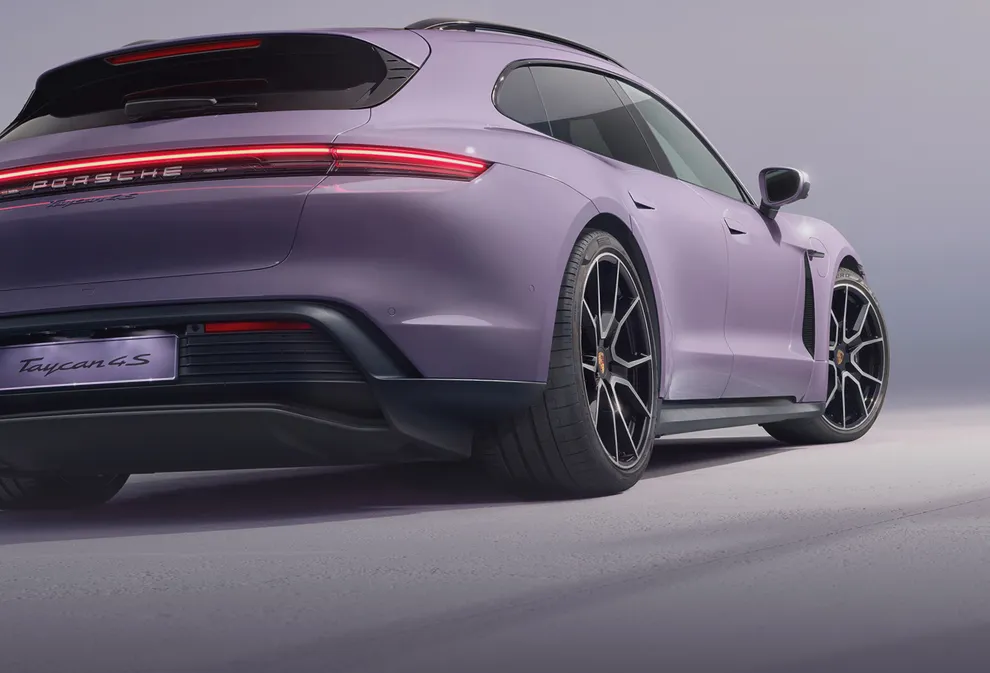Porsche Taycan 4S Sport Turismo in Provence wird vor dunklem Hintergrund angestrahlt. Blick auf Heck und Seite. 