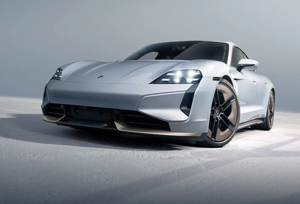 Porsche Taycan Turbo S in Ice Grey Metallic in front of a dark background. Front view.