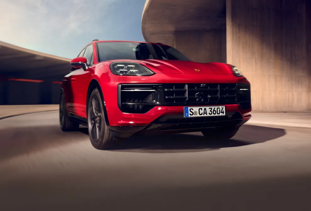 Zicht van voren op de voorkant van een optrekkende Porsche Cayenne GTS in karmijnrood.