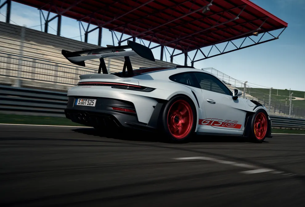 The Porsche 911 GT3 RS in Ice Grey Metallic driving on a rack track. Rear and side view.