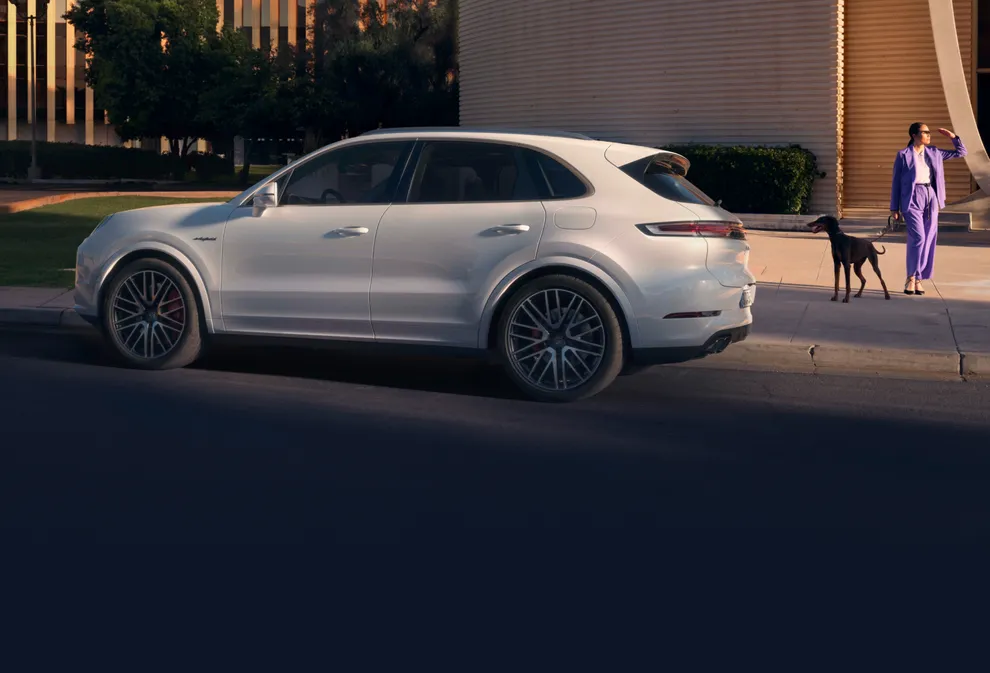Porsche Cayenne Turbo E-Hybrid en Blanc Carrara métallisé dans un environnement urbain. Vue arrière et latérale.