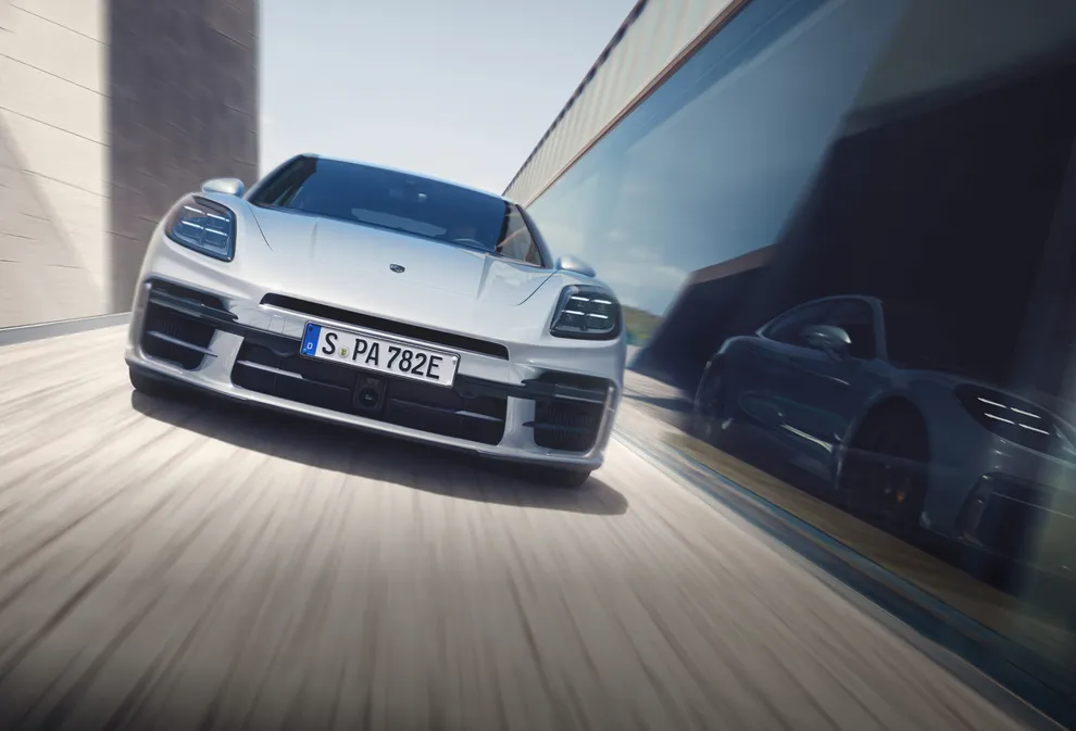 Un Porsche Panamera Turbo S E-Hybrid en color Gris Hielo Metalizado circula por una carretera. Vista de la parte delantera y el lateral.