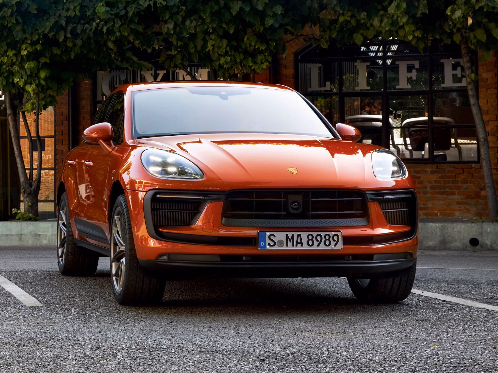 Porsche Macan S in Papaya Metallic in the city. Front view.