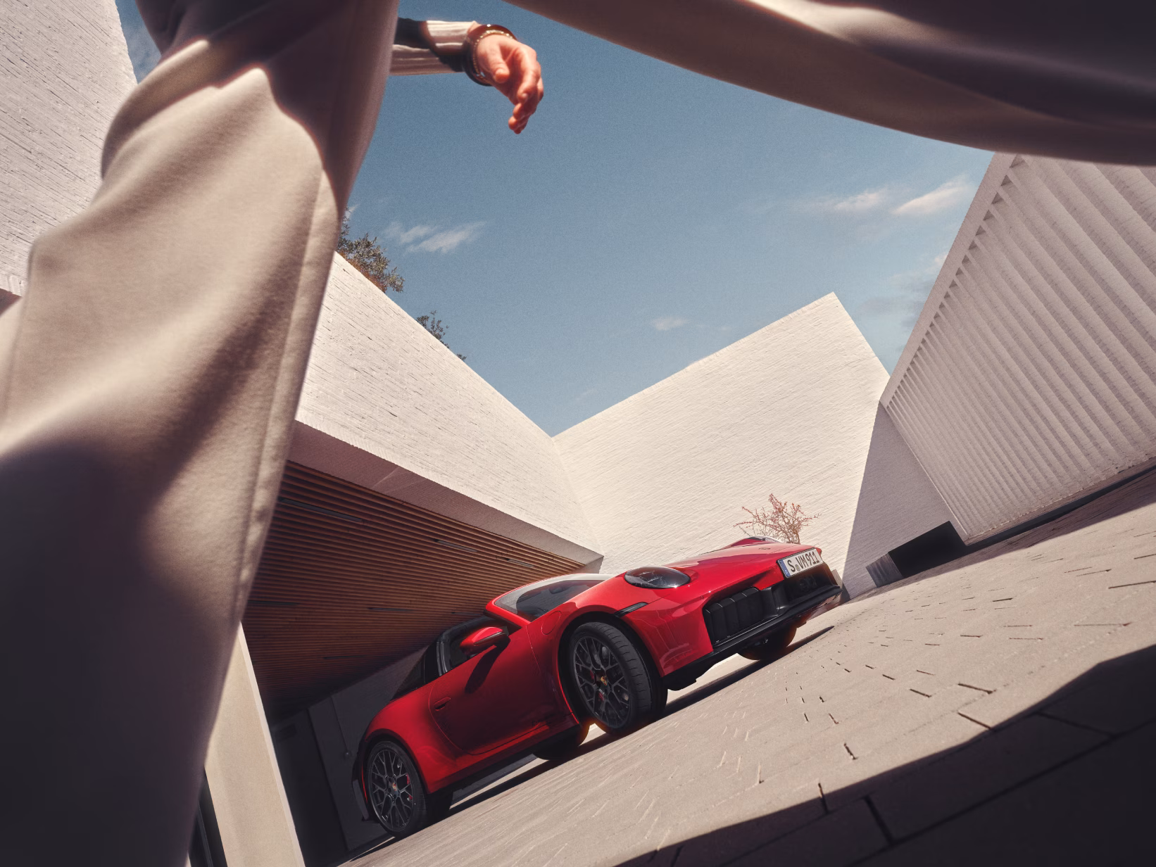 Porsche 911 Targa 4 GTS in Carmine Red parked in a courtyard. Front view from the front.