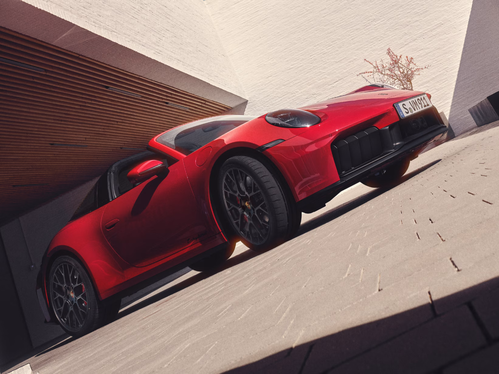 Porsche 911 Targa 4 GTS in Carmine Red parked in a courtyard. Front view from the front.