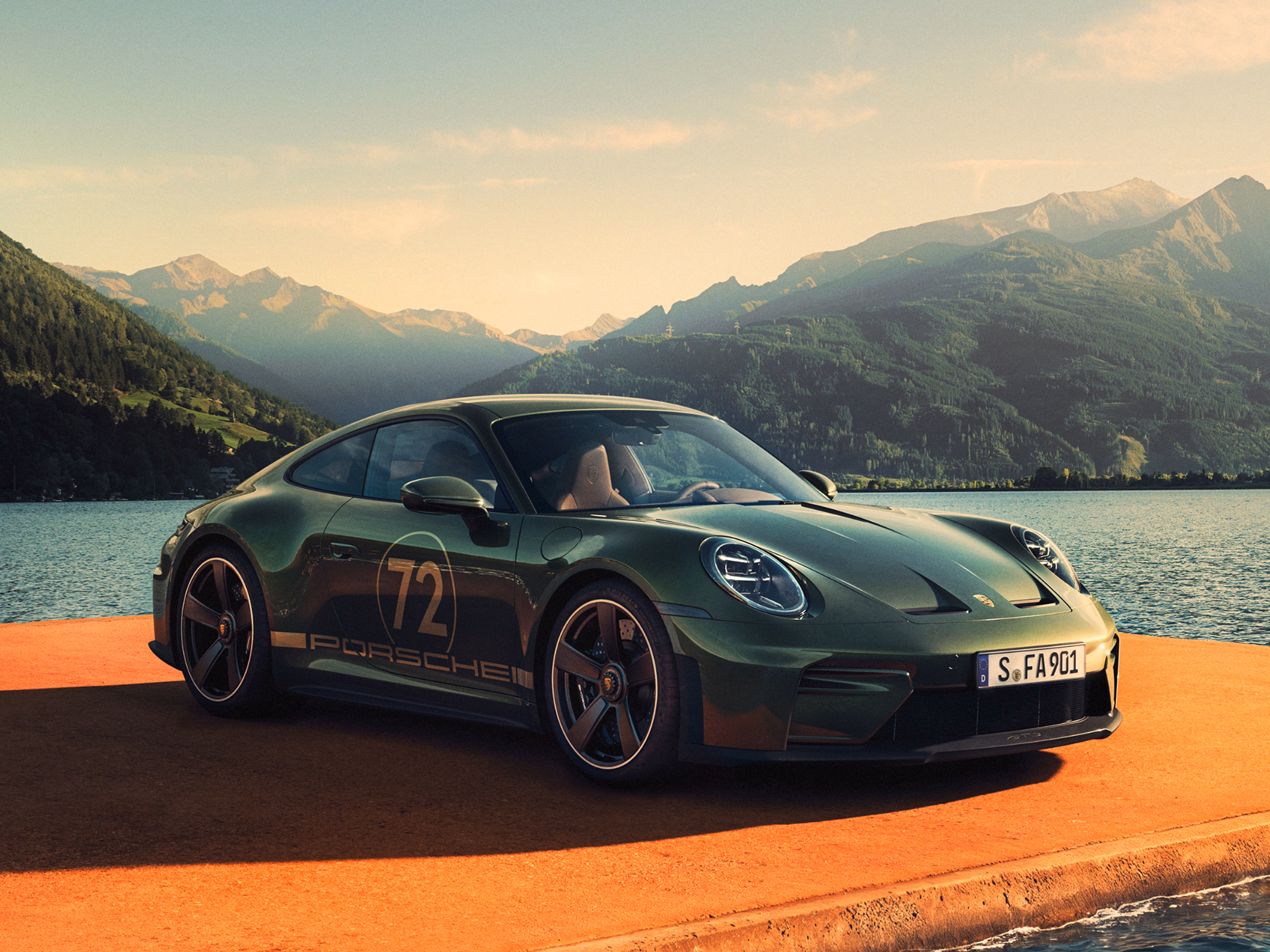Front and side view of a Porsche 911 GT3 90 F. A. in F. A. Greenmetallic on a jetty. Mountains and a lake can be seen in the background.