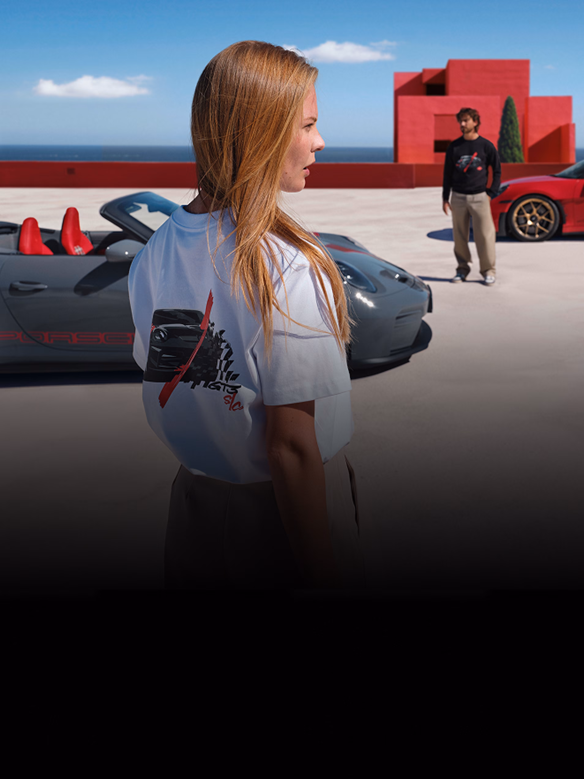 2 Personen in Klamotten von Porsche Lifestyle neben Porsche 911 GT3 C/S Fahrzeugen.