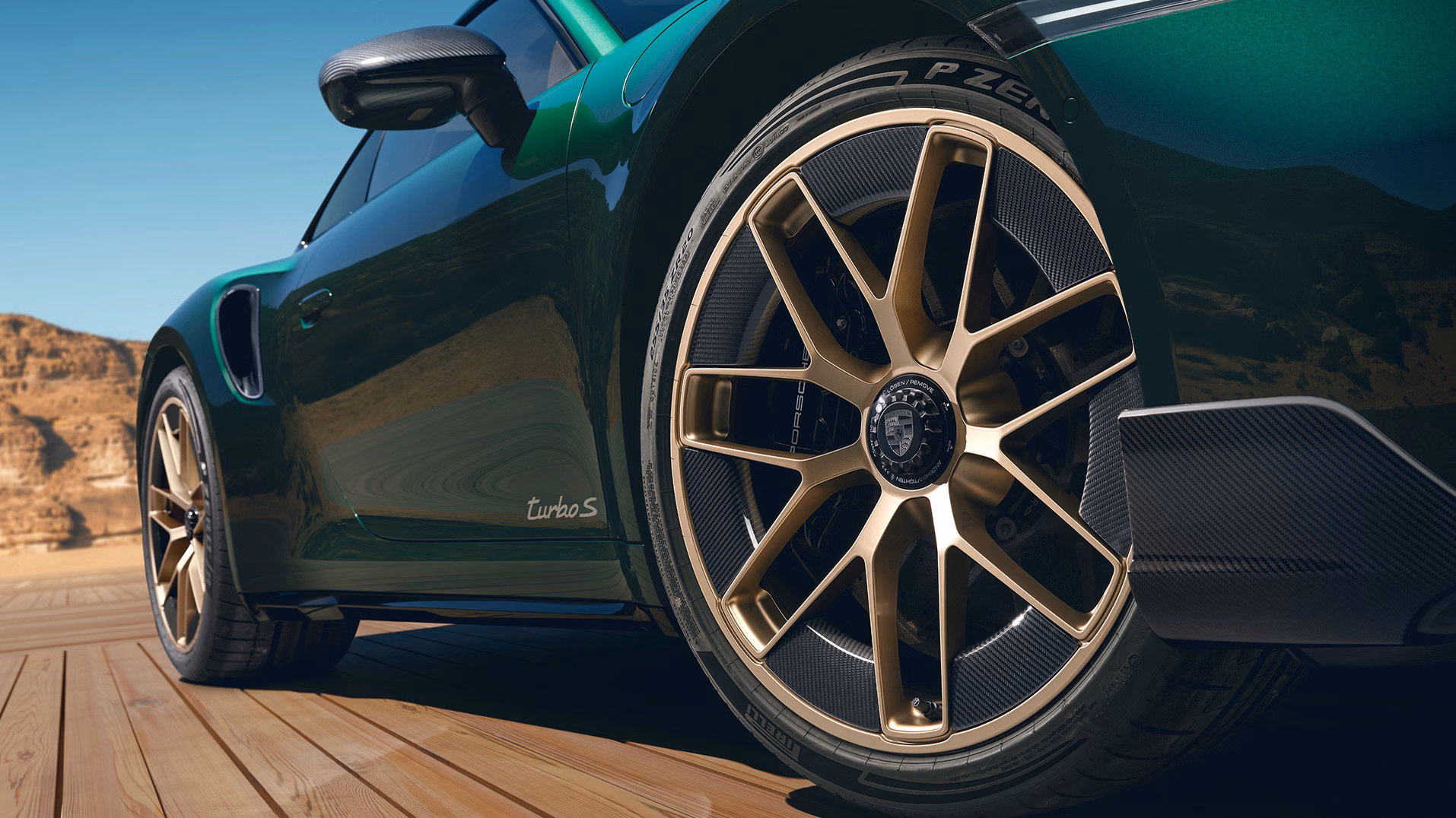 View of the rear and side of a Porsche 911 Turbo S in Oak Green Metallic Neo, standing in a courtyard.