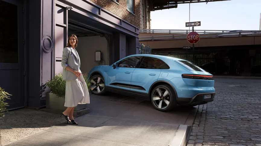 The Macan Electric in Frozen Blue Metallic driving into a home garage.
