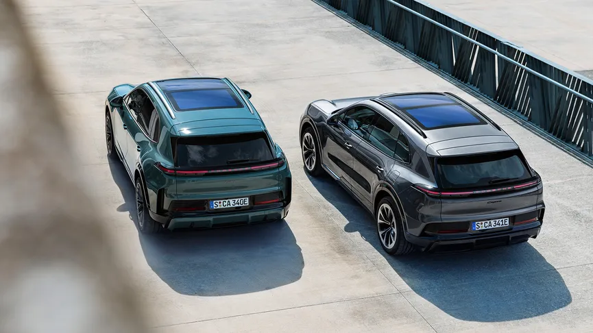 Two Porsche Cayenne Electric Models parked side-by-side in a minimalist concrete courtyard.