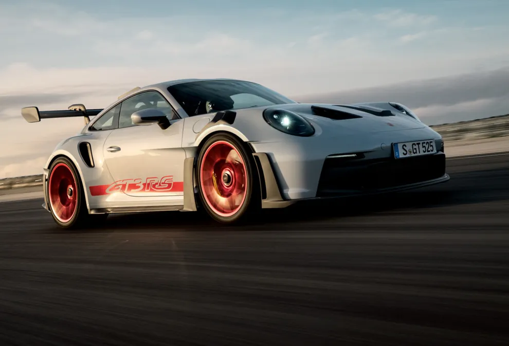 Porsche 911 GT3 RS in ijsgrijs metallic rijdt op het circuit. Zicht op de voorzijde en de zijkant.