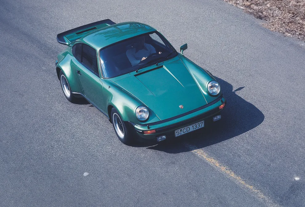 Blick von oben auf die Front und Seite eines fahrenden Porsche 911 Turbo (930).  