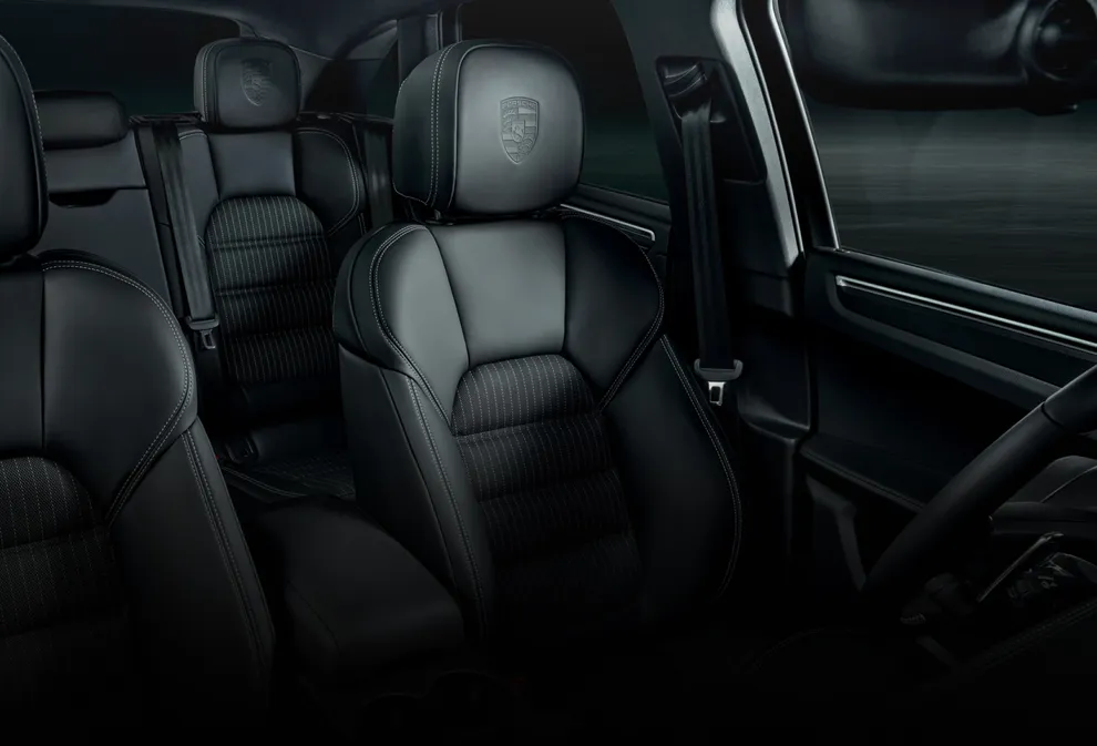 Porsche Macan T interior: detailed view of the driver seat with Porsche crest on the headrests.