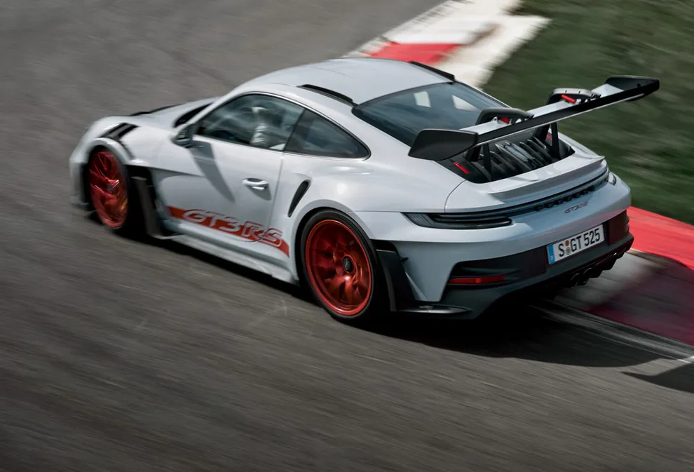 The Porsche 911 GT3 RS in Ice Grey Metallic taking a corner on a race track. Top rear view of the rear end.