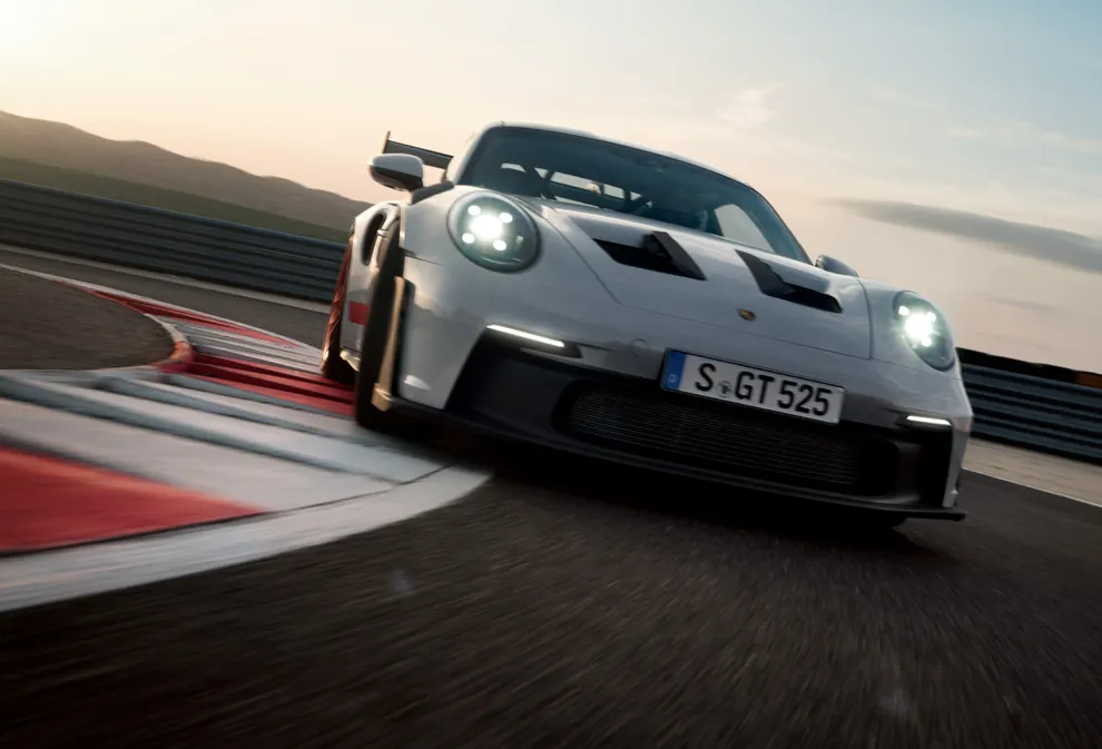 The Porsche 911 GT3 RS in Ice Grey Metallic taking a corner on a race track. Front view from the front.