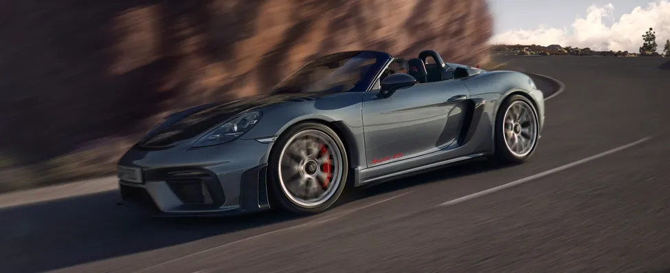 Porsche 718 Spyder RS in Vanadiumgrijs metallic en zonder kap rijdt door de bocht. Zicht vanaf de onderkant op de voorkant en zijkant.