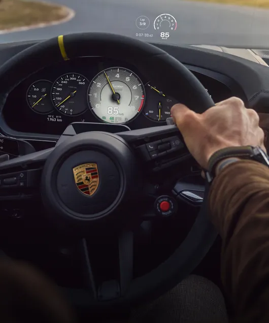 Interior del Porsche Cayenne Turbo E-Hybrid Coupé con paquete GT: vista detallada del Head-Up Display durante la marcha en un circuito.