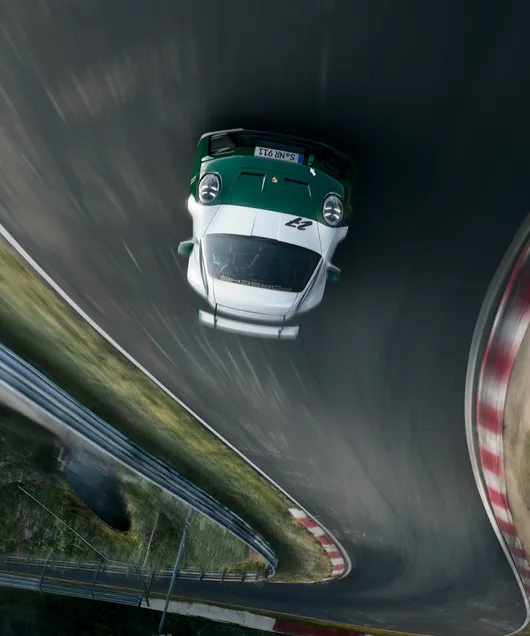 Blick von vorne auf die Front des auf der Rennstrecke Nürburgring fahrenden Porsche 911 GT3 100 Jahre Nürburgring. Das Bild steht auf dem Kopf.