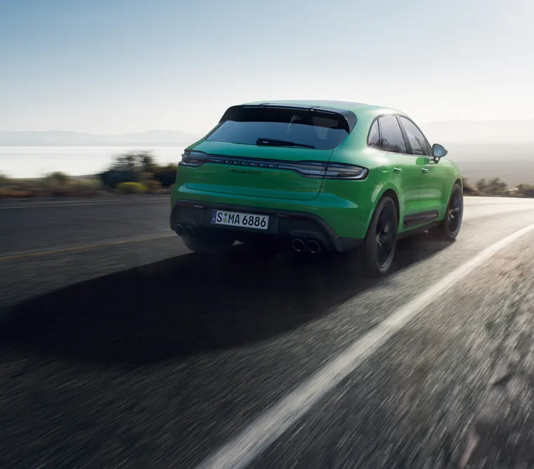 蟒蛇綠保時捷 Macan GTS 行駛在鄉間小路上。後端後視圖