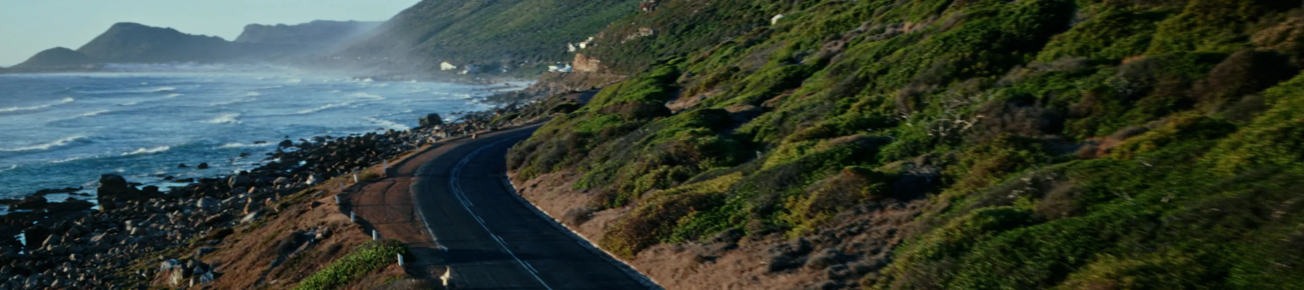 Ein Porsche Macan fährt eine Küstenstraße entlang.