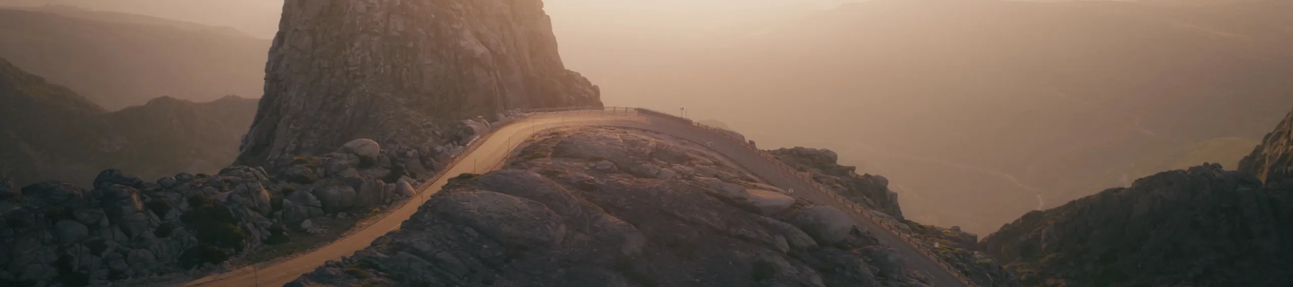 View over a wide, Green landscape with forest and mountains and a road crossing it.