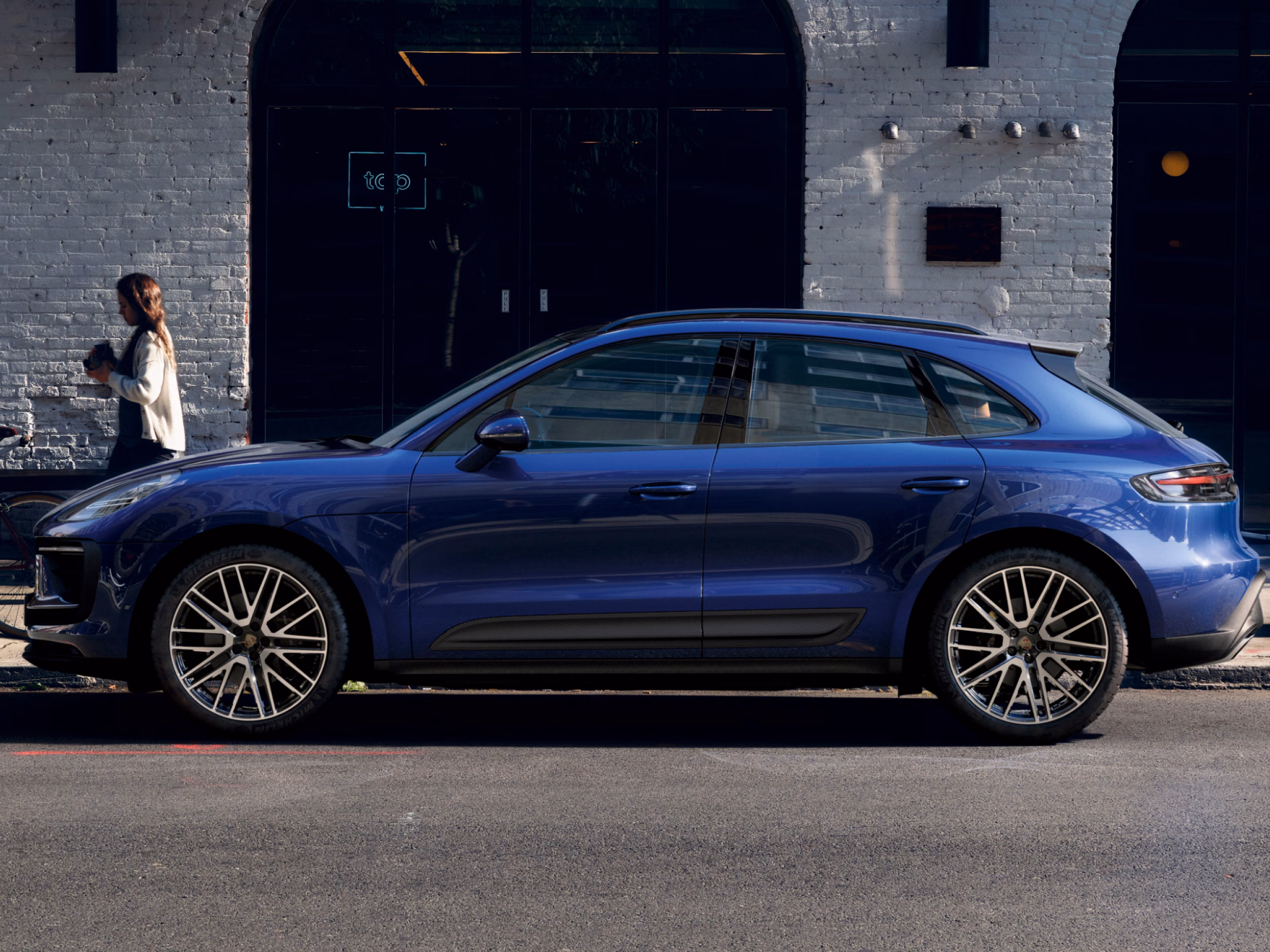 Porsche Macan in Gentian Blue Metallic on a street. Side view.