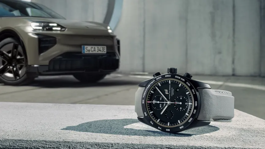 A Chronograph from Porsche Design next to a Porsche Cayenne Coupé Electric.